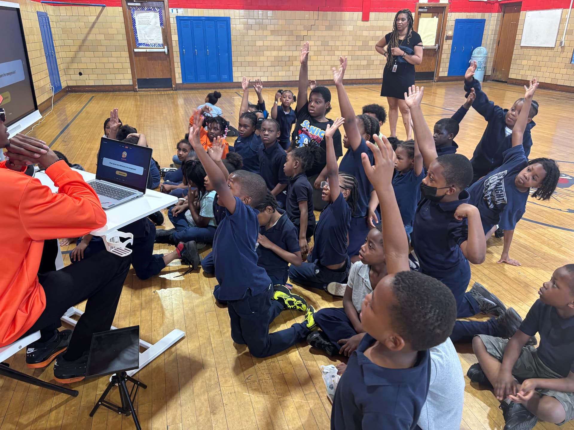 Students eagerly raising hands during a Rocket Adventures reading assembly